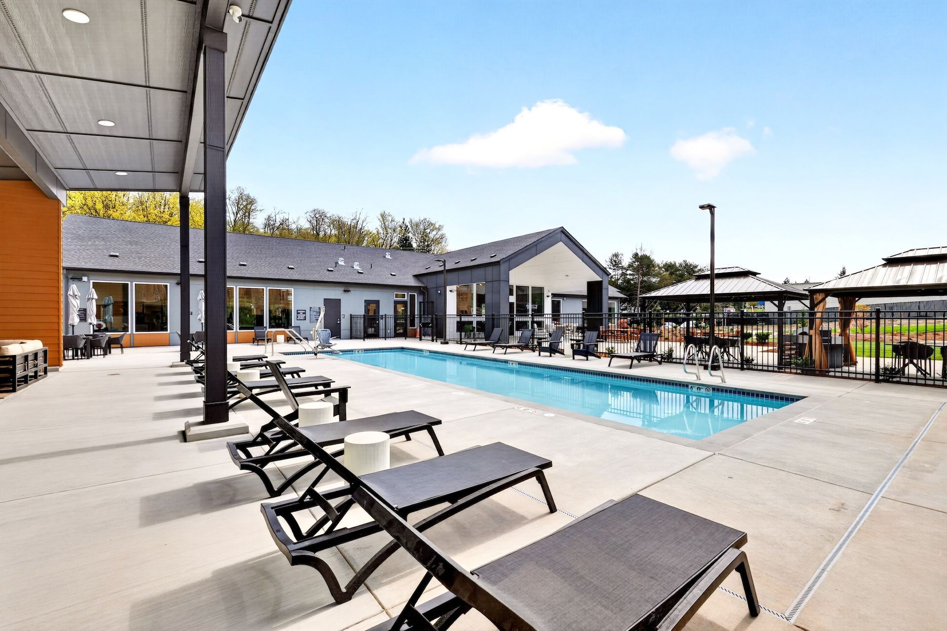 Outdoor swimming pool with lounge chairs beside a modern apartment courtyard