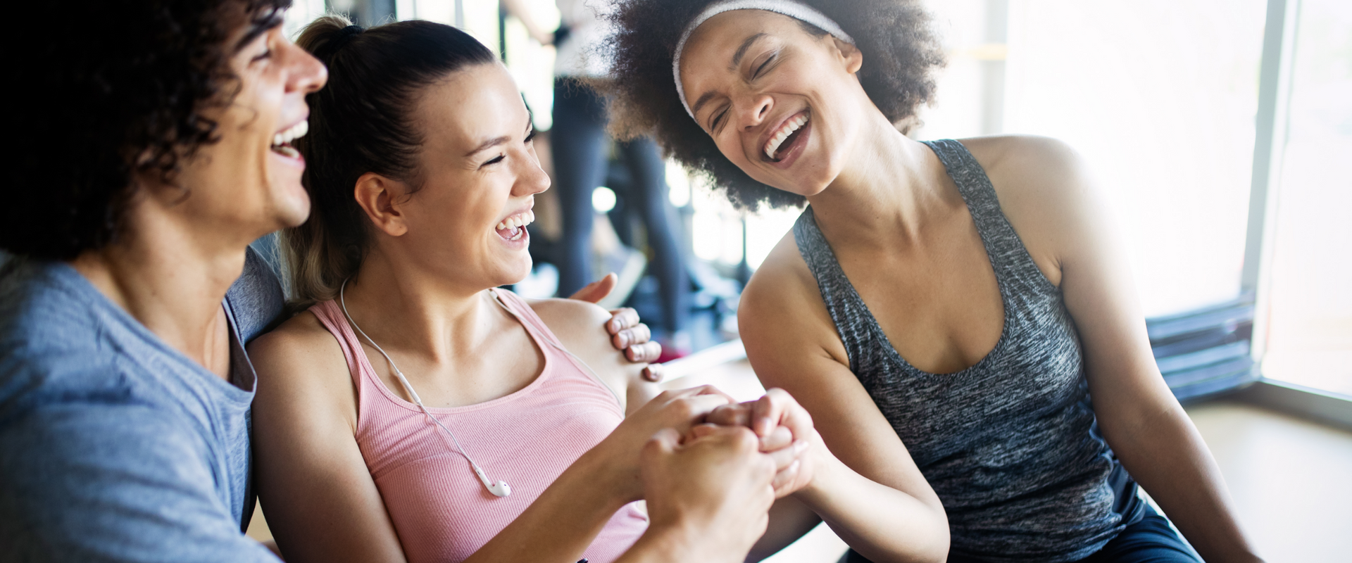 Three people laughing together in a gym setting.