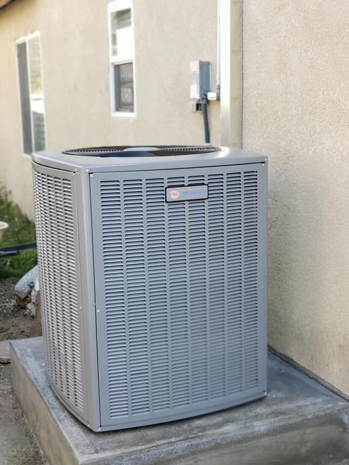 A large gray air conditioner is sitting on the side of a building.
