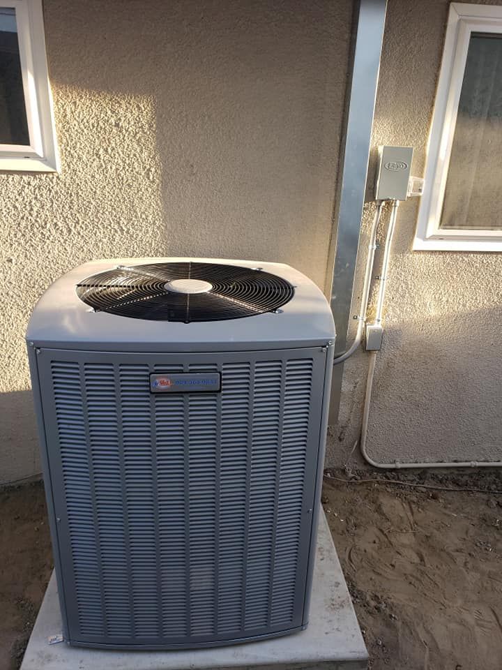 An air conditioner is sitting outside of a house next to a window.