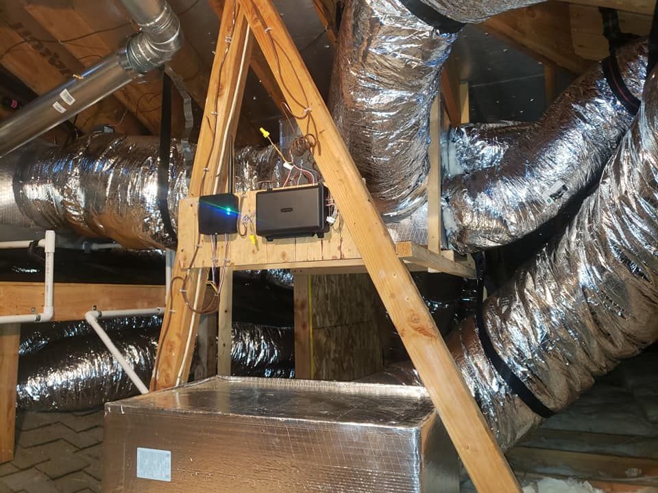 A bunch of ducts are hanging from the ceiling in an attic