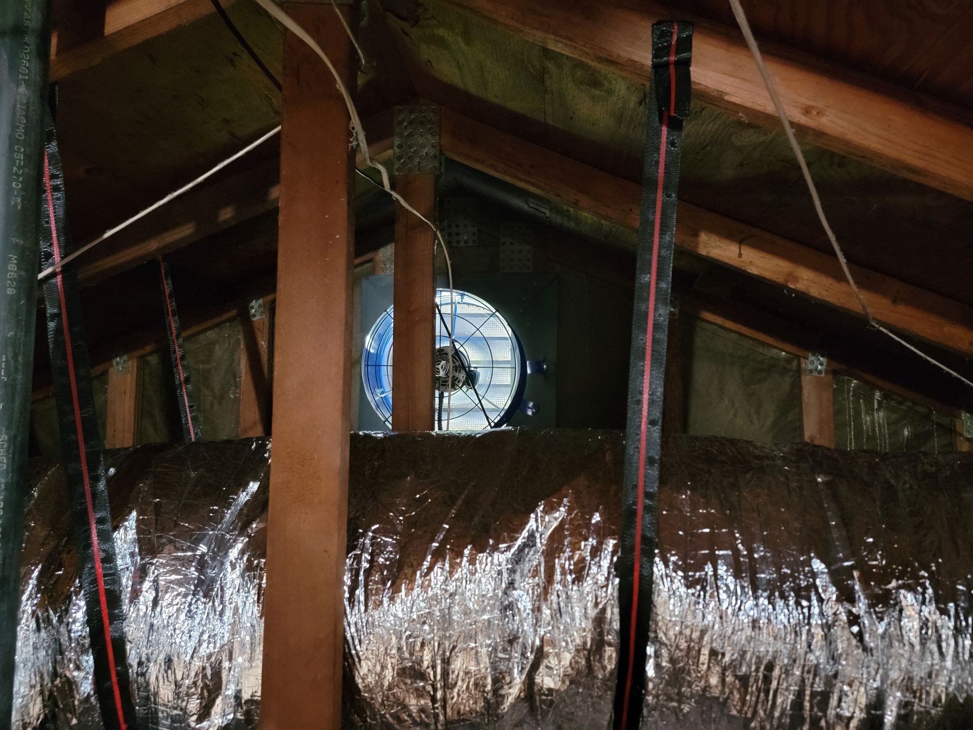 A fan is hanging from the ceiling of an attic