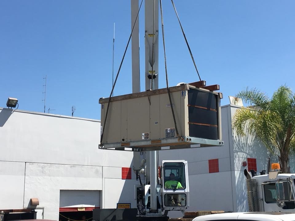 A large box is being lifted by a crane in front of a building