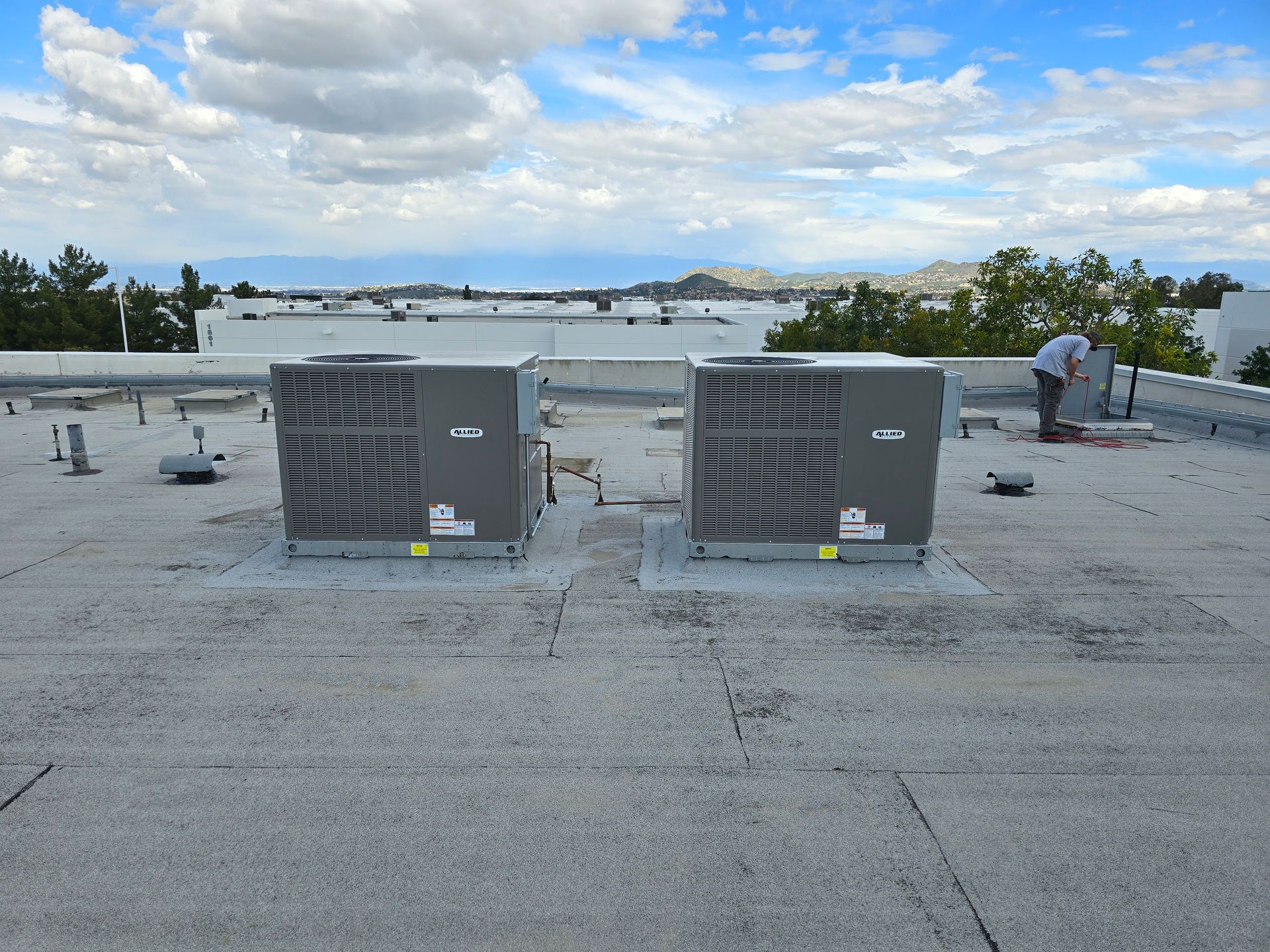 Two air conditioners are sitting on top of a roof.