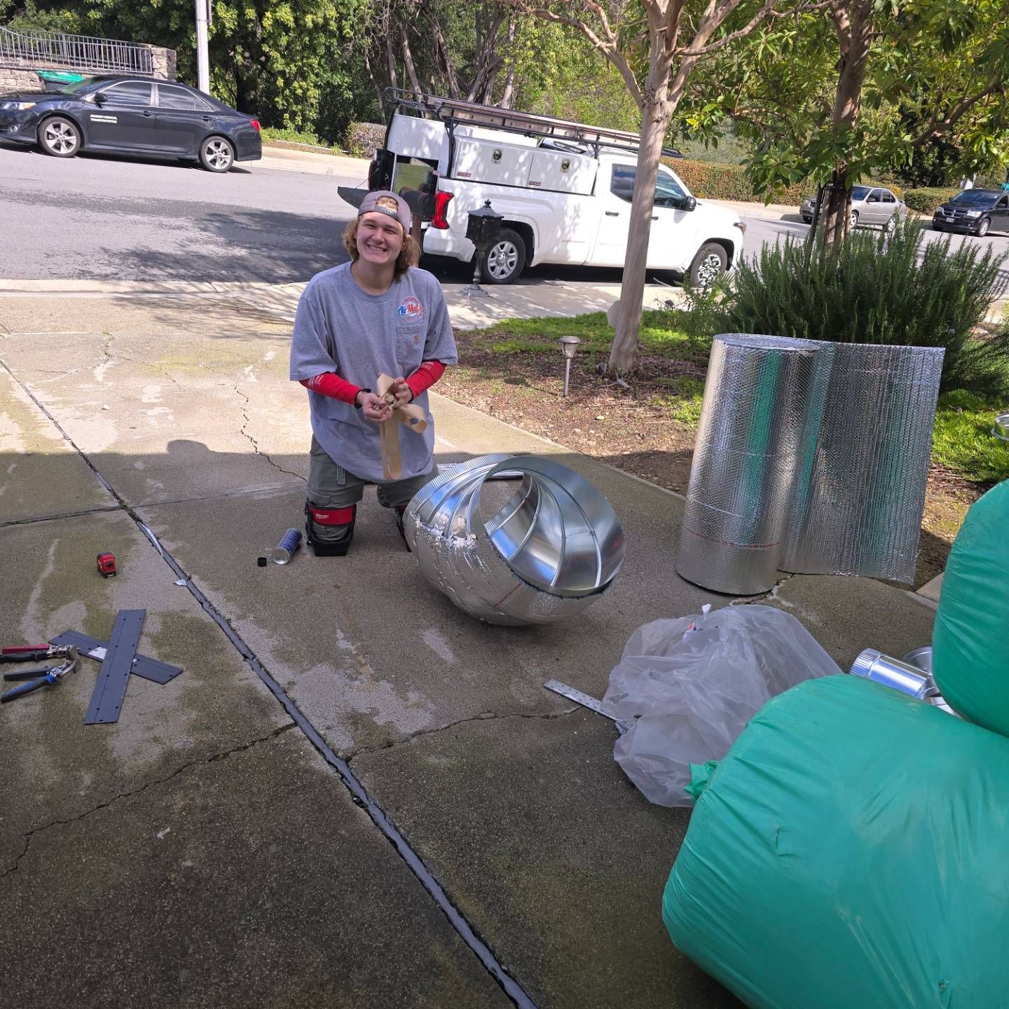 A man is kneeling down next to a large metal ball