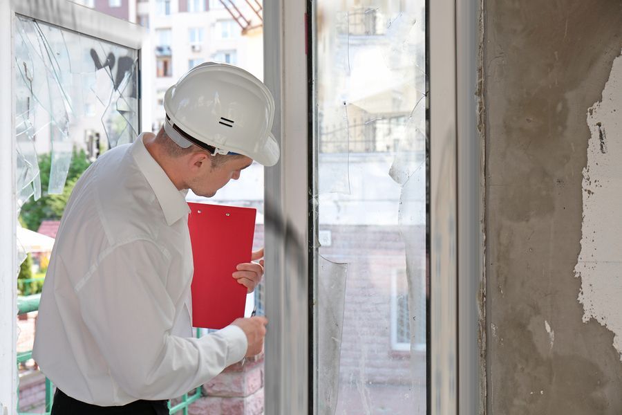 Worker in hard hat inspecting a window frame inside a building under renovation