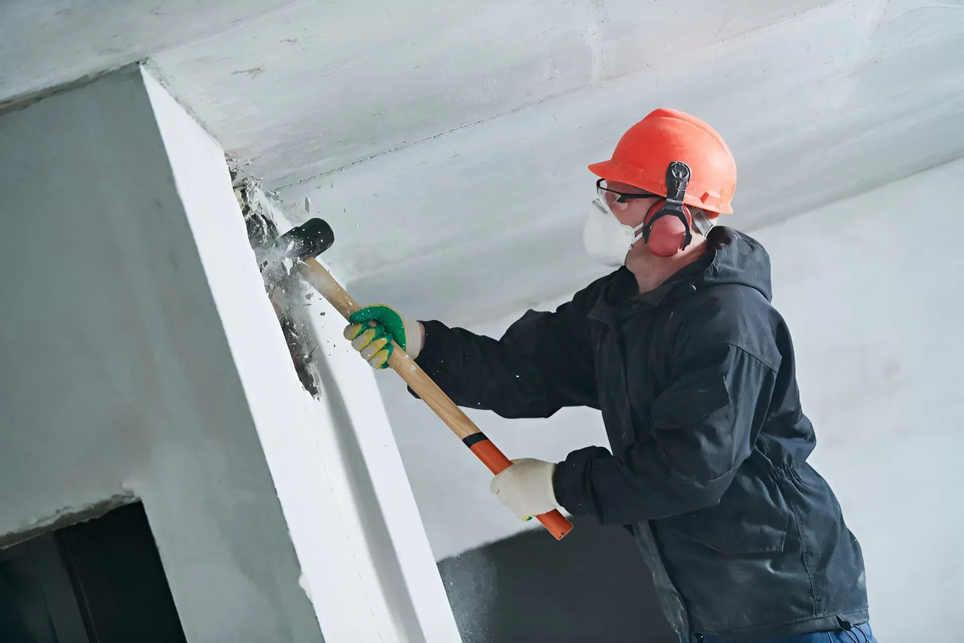 Construction Worker in Hard Hat Using a Hammer to Demolish a Wall — Boland Contracting In Wellington, NSW