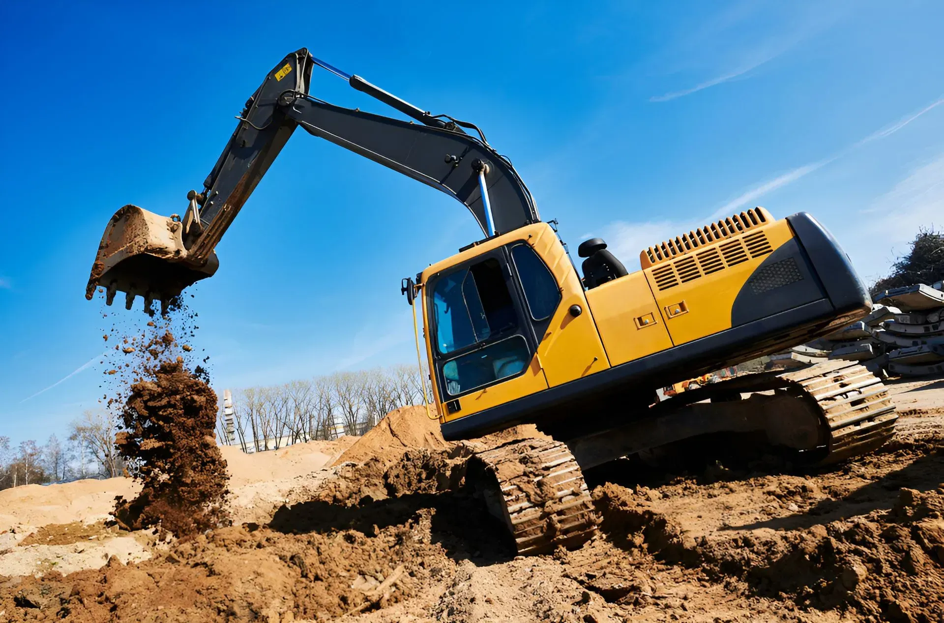 Yellow Excavator Digging Dirt Bright Blue Sky in Background — Boland Contracting In Cobar, NSW