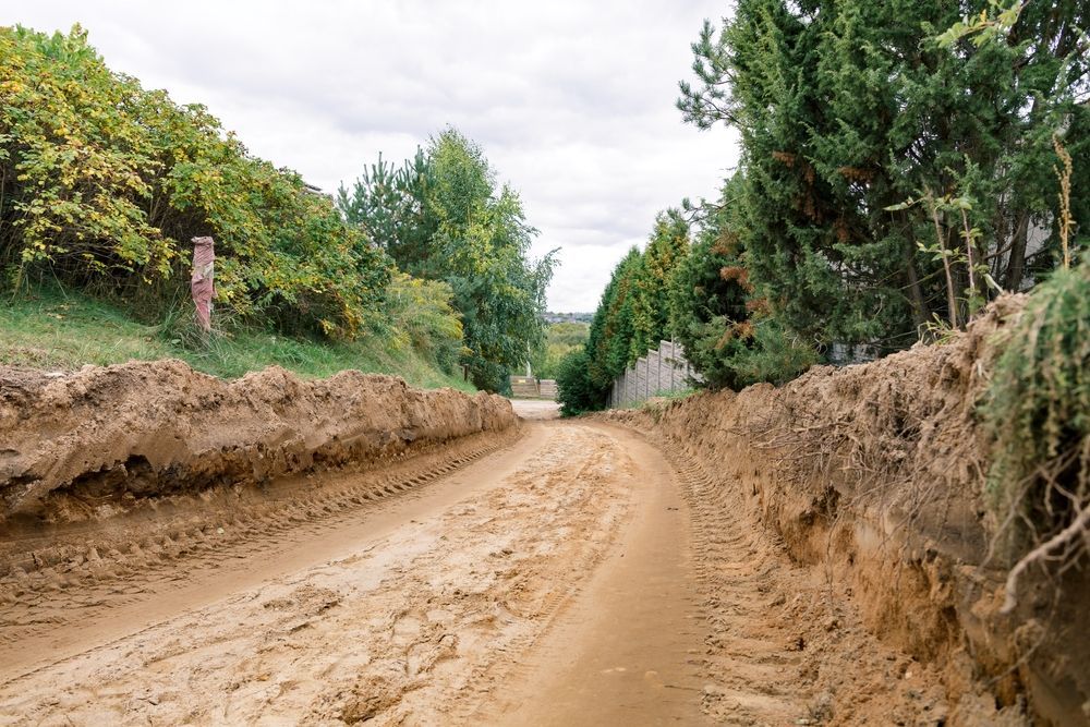 Dirt Road Cut Between Two Earth Berms Lined With Trees — Boland Contracting In Wellington, NSW