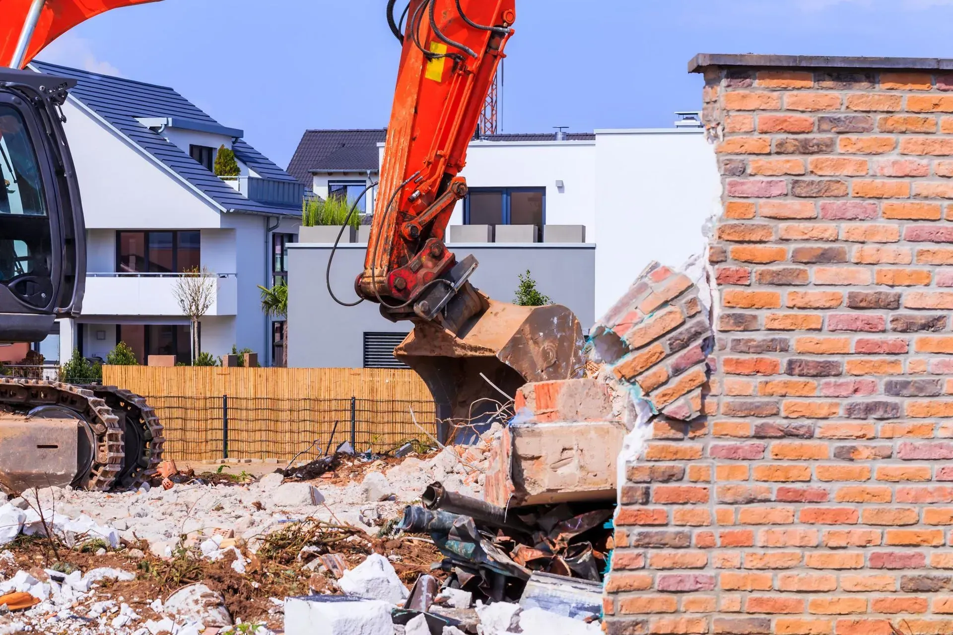 An Excavator Demolishing a Brick Wall in a Residential Area — Boland Contracting In Wellington, NSW
