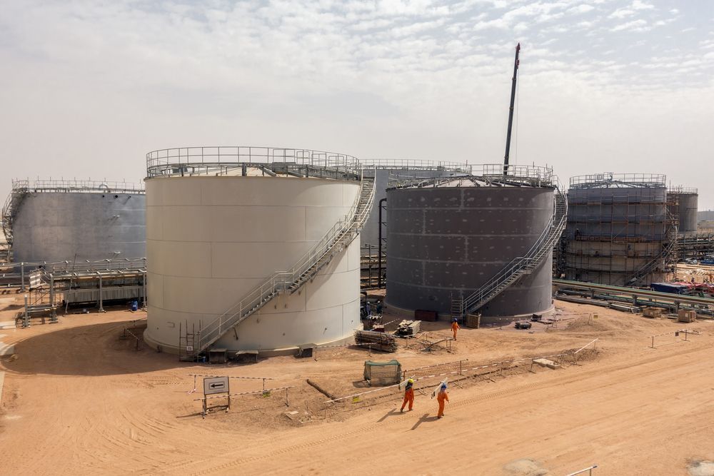 Large Industrial Storage Tanks With Workers in Orange Suits — Boland Contracting In Wellington, NSW
