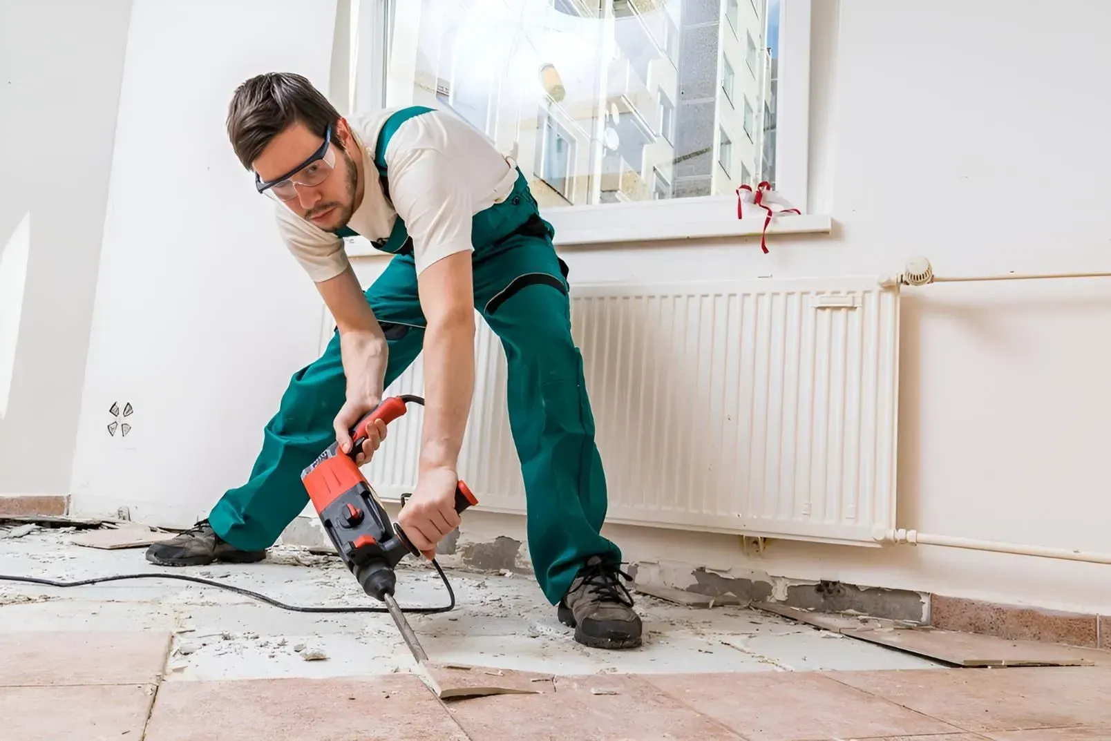 Man in Green Work Clothes and Safety Glasses Using a Jackhammer to Remove Flooring — Boland Contracting In Cobar, NSW