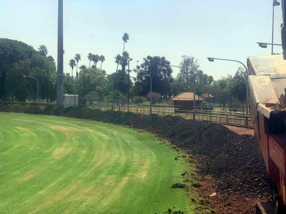 Green Grass Field Pile of Dirt, Trees and a Building With a Fence — Boland Contracting In Wellington, NSW