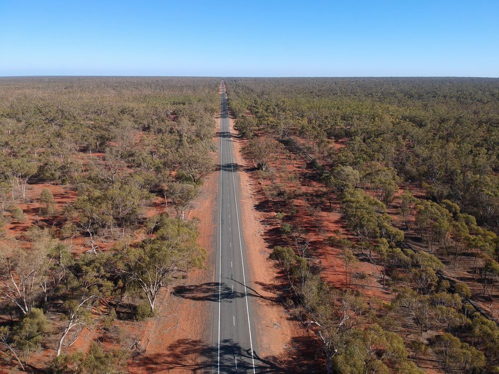 A Long, Straight Road Cuts Through a Red-earth Forest Under a Clear Blue Sky — Boland Contracting in Bourke, NSW