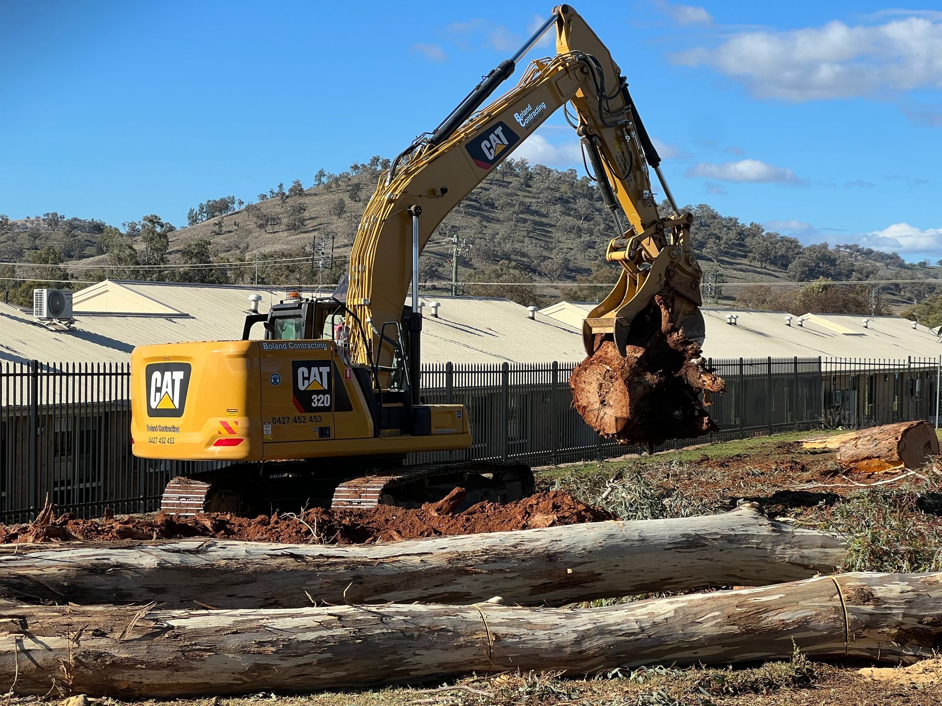 Two Yellow Construction Vehicles on a Muddy Site With a Pile of Rubble and a Blue Sky — Boland Contracting In Wellington, NSW