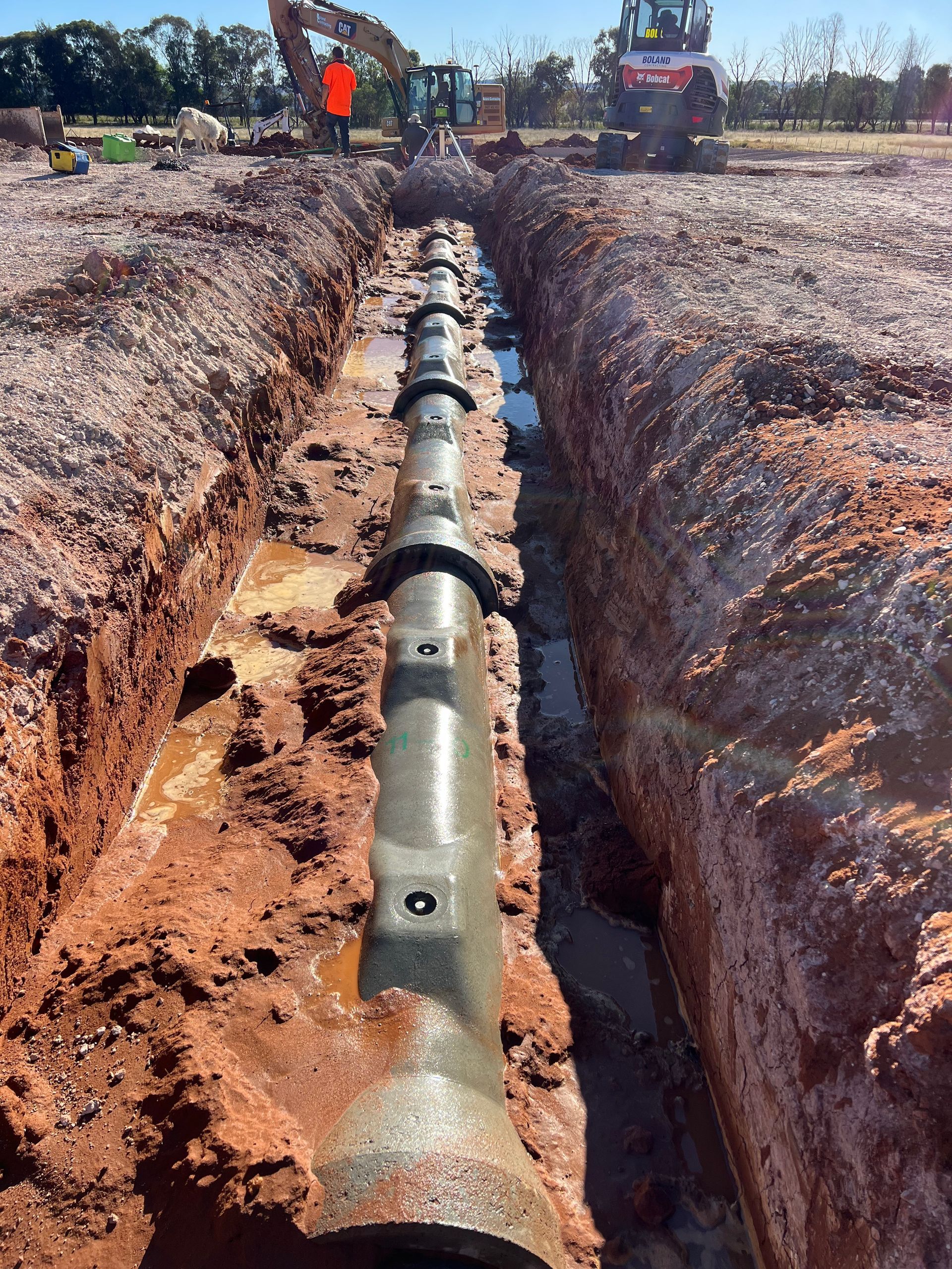 A Trench With Installed Sewer Pipes Construction Equipment — Boland Contracting In Wellington, NSW
