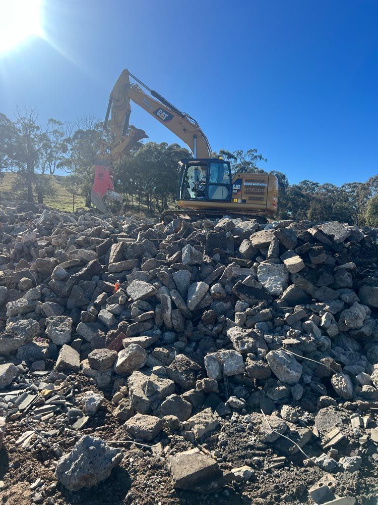 Excavator on a Pile of Rubble, Under a Bright Blue Sky — Boland Contracting In Wellington, NSW