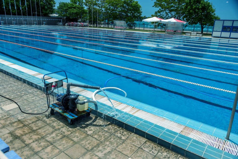 Blue Outdoor Swimming Pool With Lane Lines and Pool Cleaning Equipment on the Deck — Bromage Pool Heating in Palmview, QLD