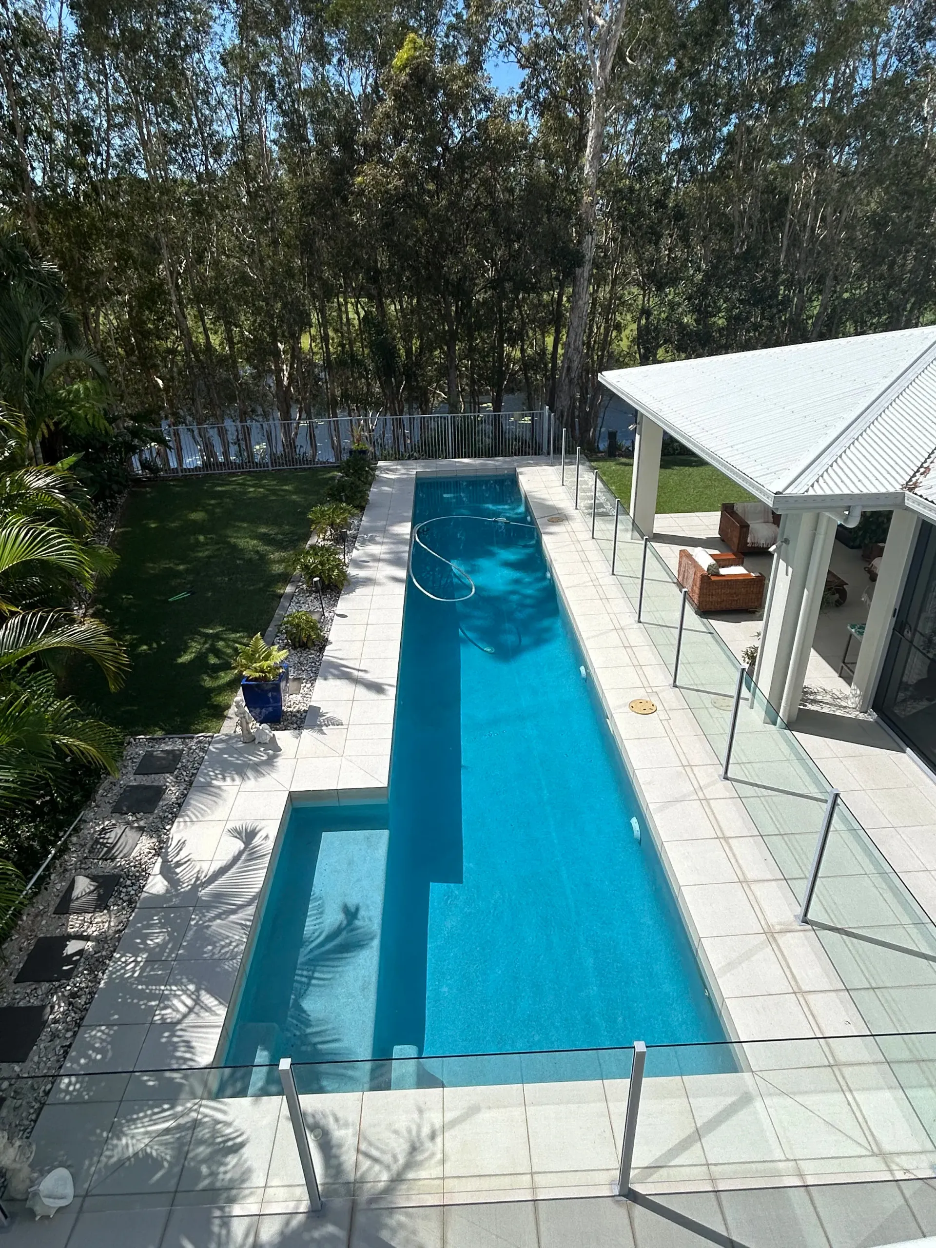 Narrow Backyard Lap Pool Beside a White Patio  — Bromage Pool Heating in Palmview, QLD