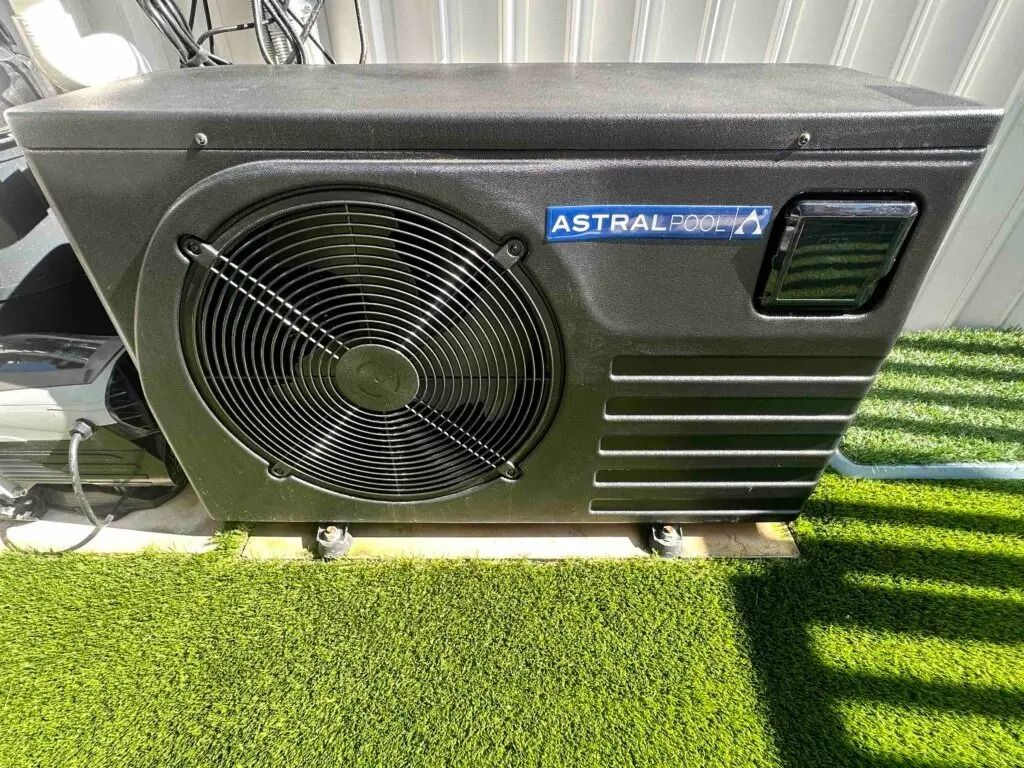 Black Astral Compressor Unit With Large Fan, Sitting Outdoors on Artificial Grass — Bromage Pool Heating in Palmview, QLD