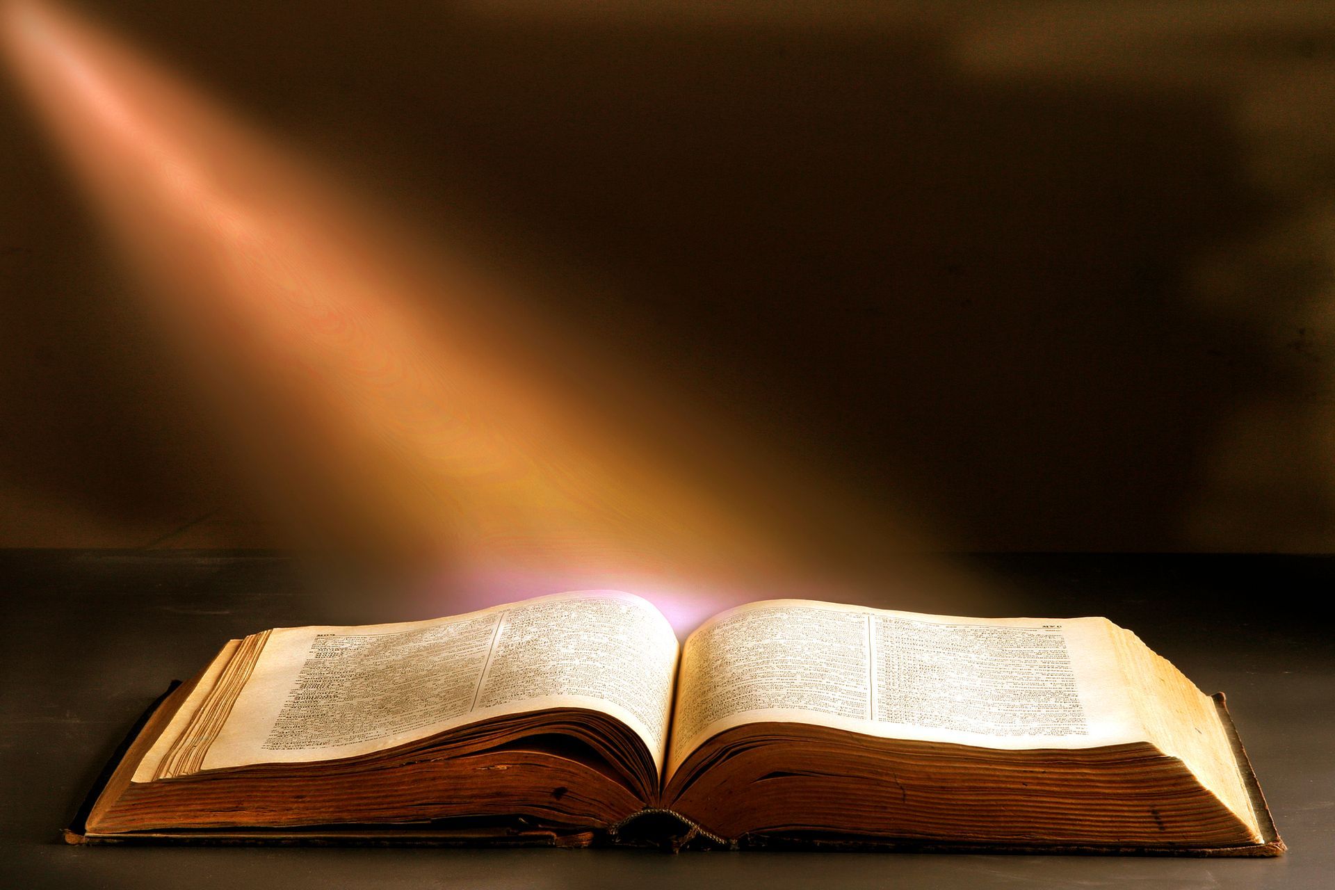 an open bible with a light shining through the pages
