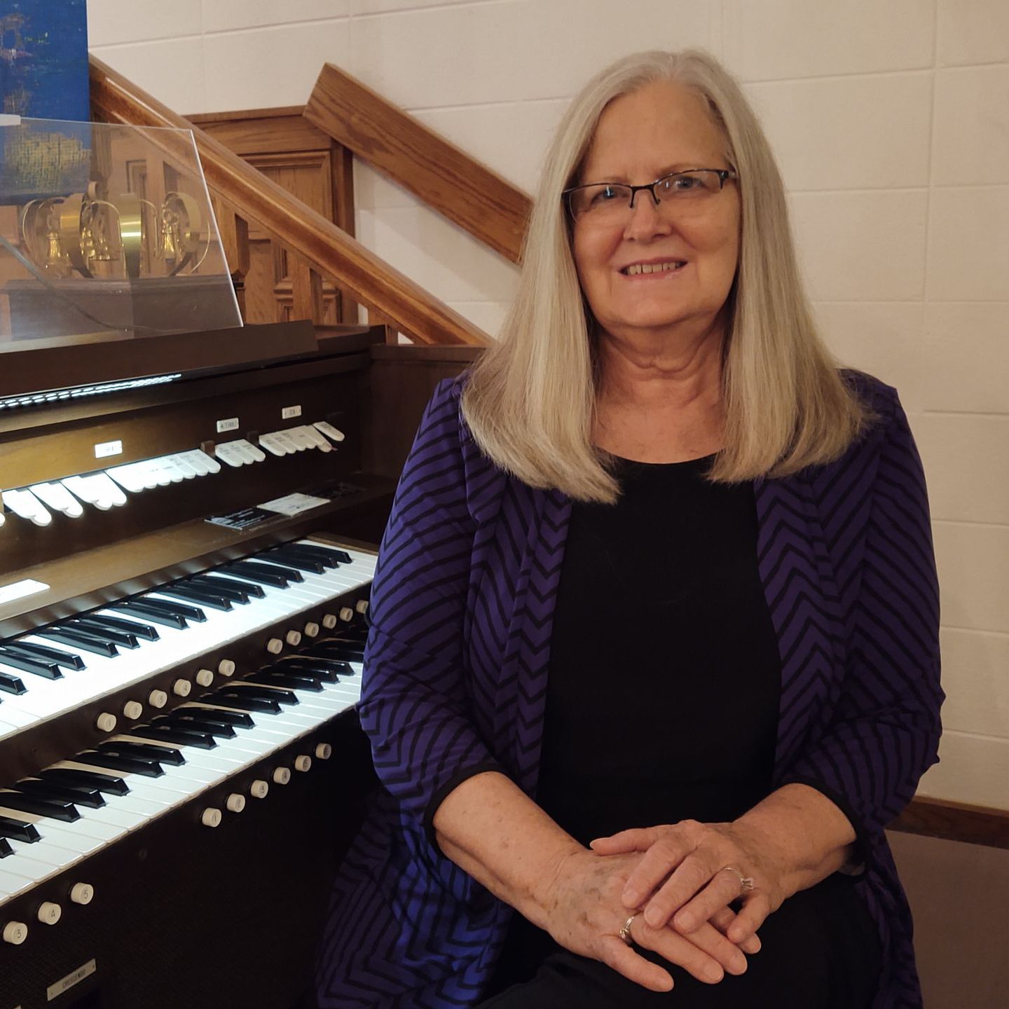 a woman is sitting in front of an organ and smiling