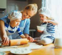 A woman and two children are preparing food in a kitchen.