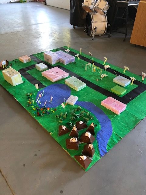 A model of a city is sitting on the floor in a room with a drum in the background.