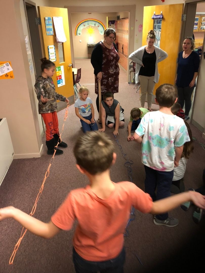 A group of children are playing a game in a hallway