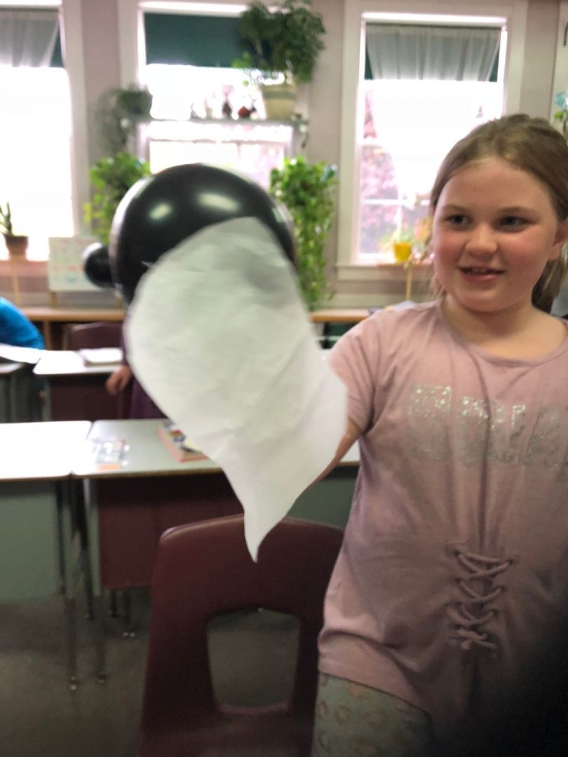 A girl in a pink shirt is holding a black and white balloon