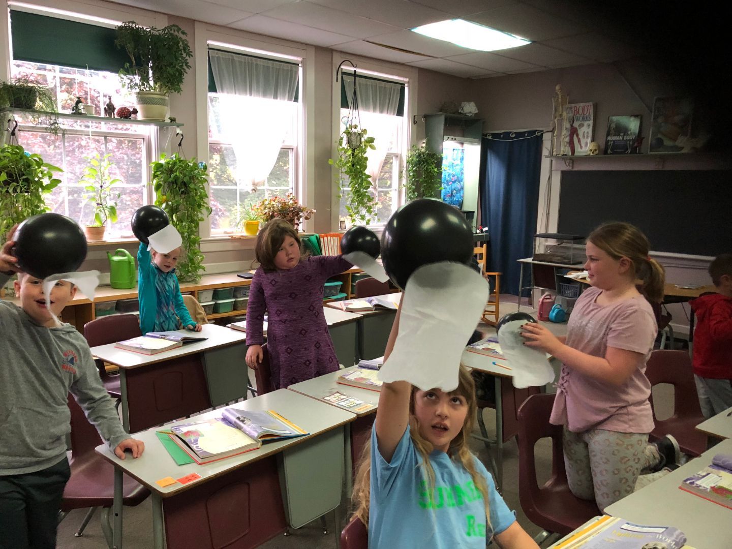 A group of children are playing with balloons in a classroom