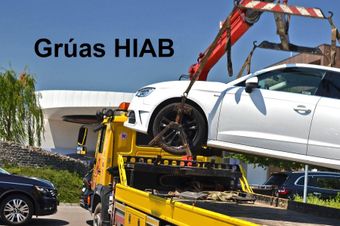 Un coche blanco está siendo levantado por una grúa en una grúa.