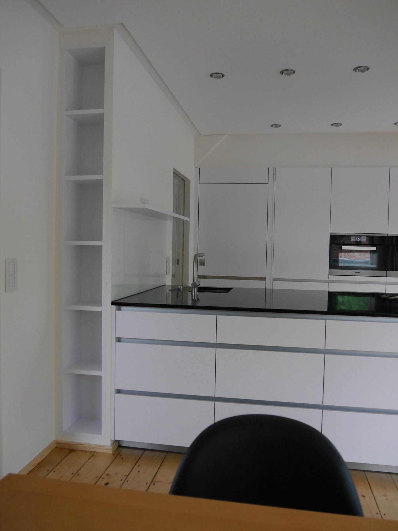 Eine Küche mit weißen Schränken und einer schwarzen Arbeitsplatte