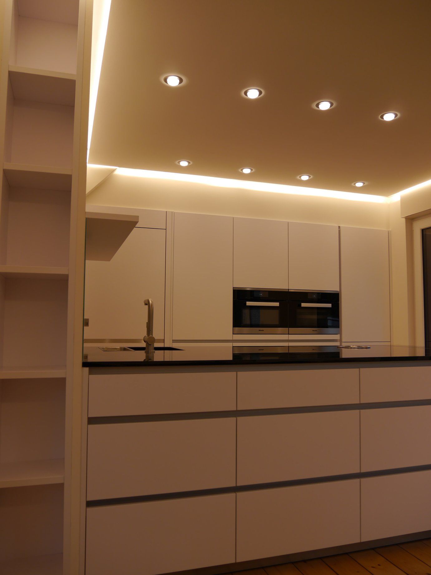 Eine Küche mit weißen Schränken und einer schwarzen Arbeitsplatte