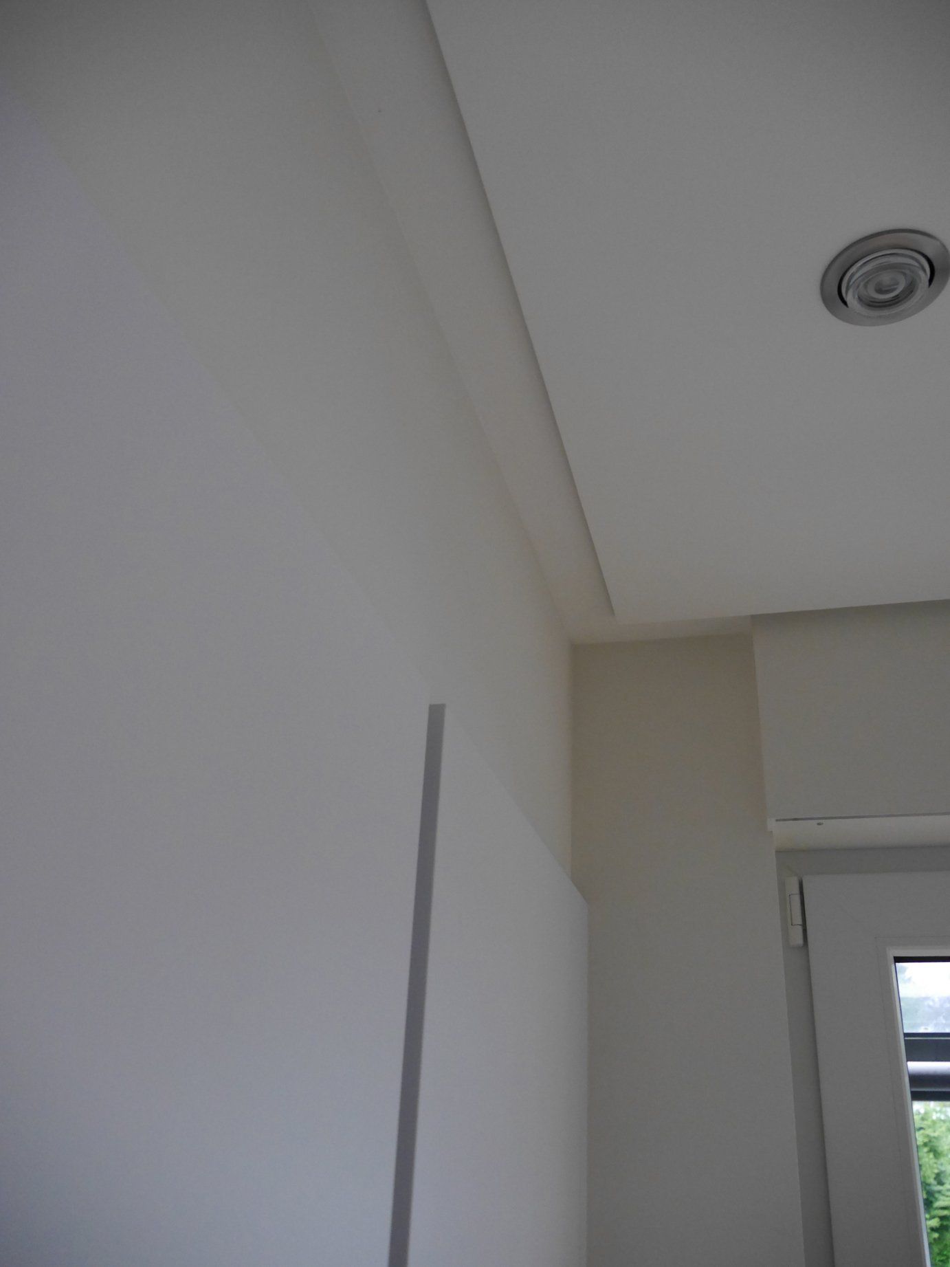 Eine weiße Wand mit einer Tür und einer Deckenleuchte