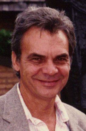 A man in a suit and white shirt is smiling for the camera.