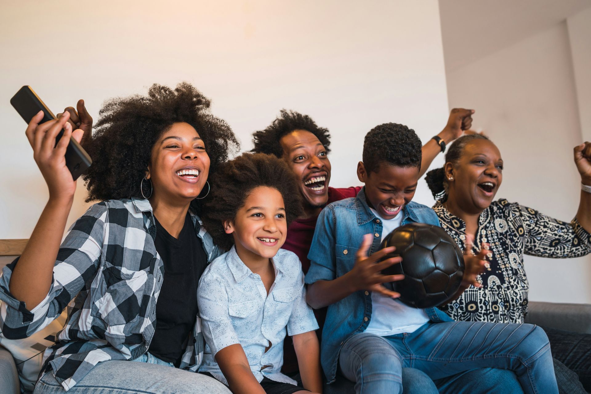 A family is sitting on a couch watching a soccer game.