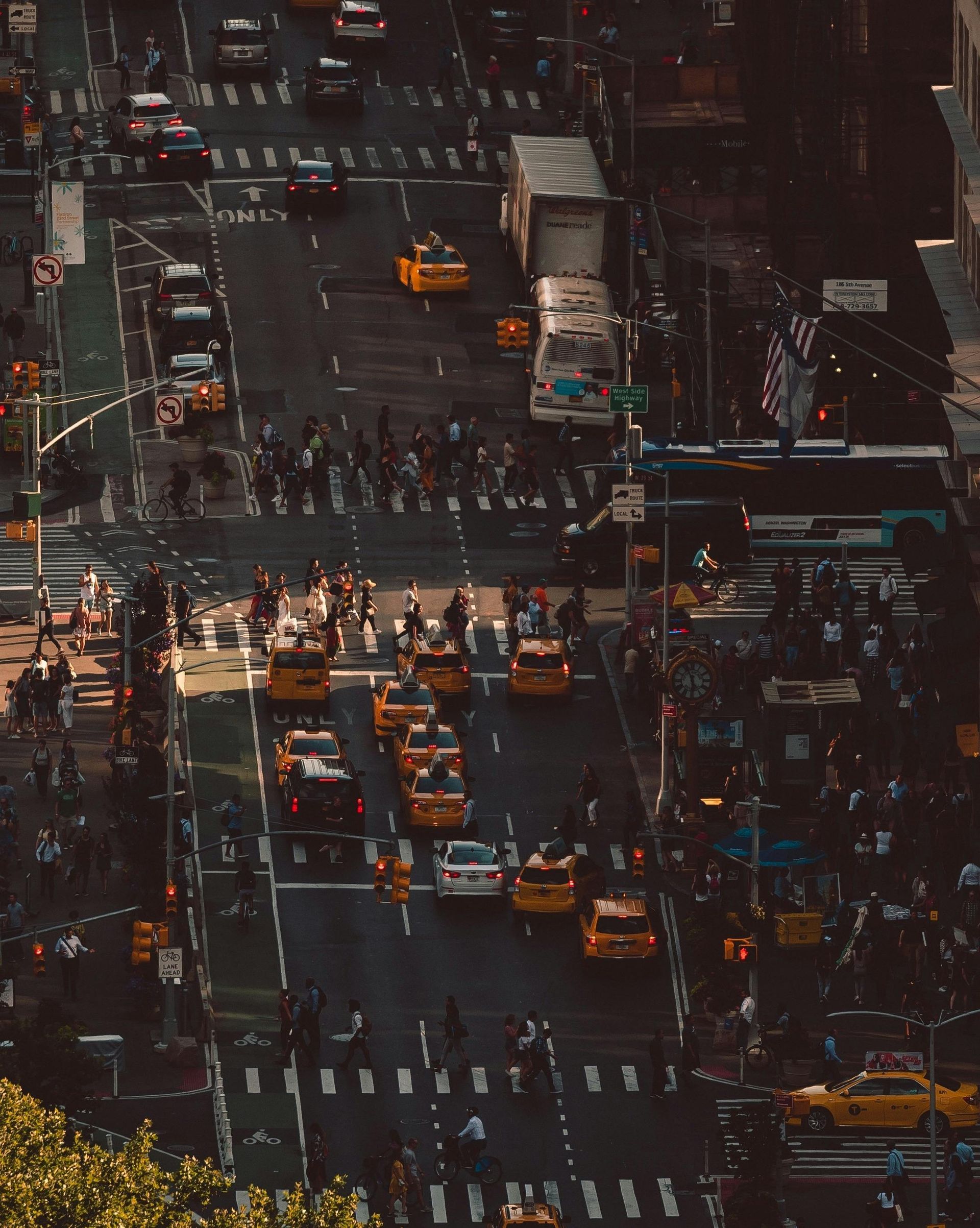 An aerial view of a busy city street with taxis and pedestrians