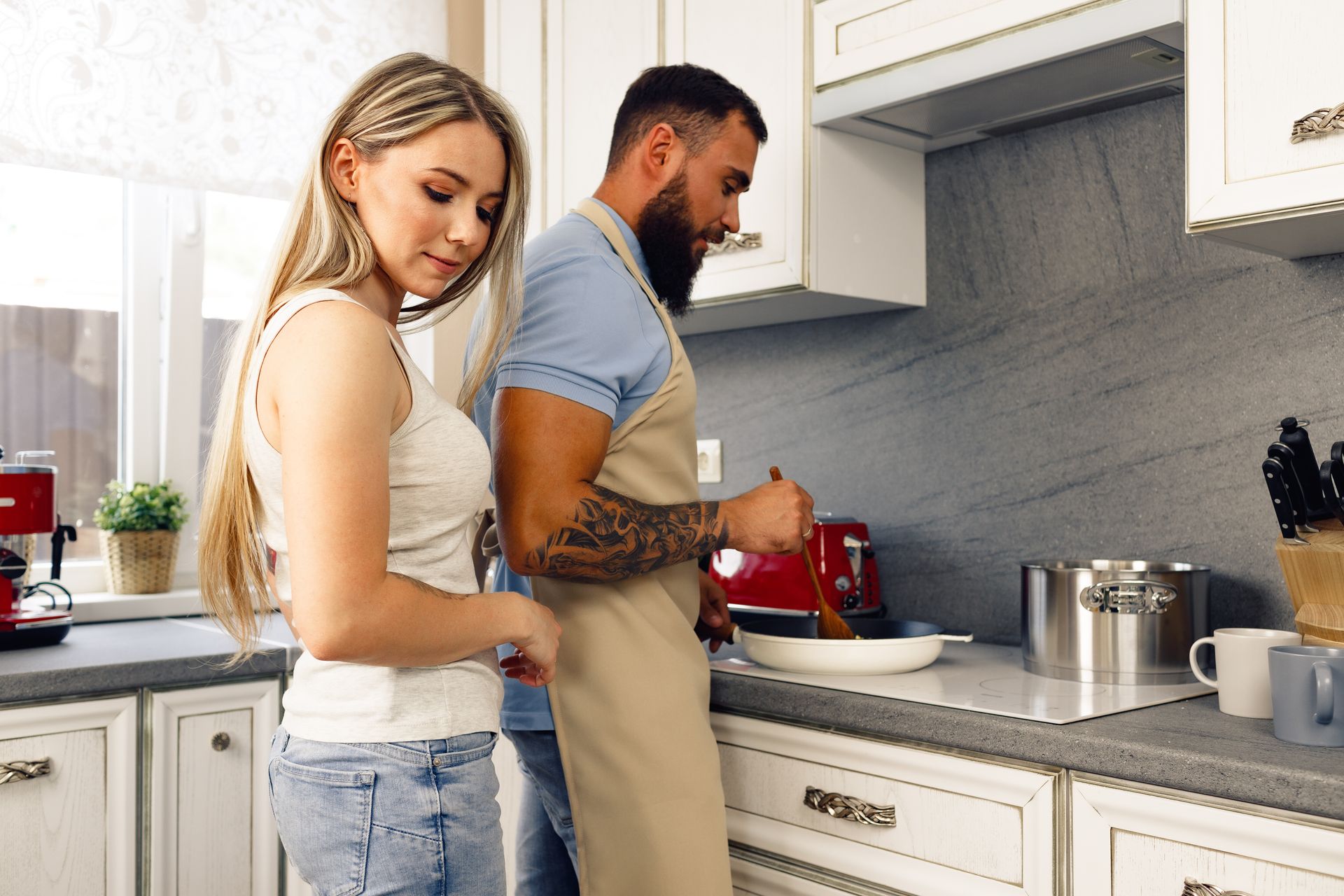 A man and a woman are standing in a kitchen preparing food.