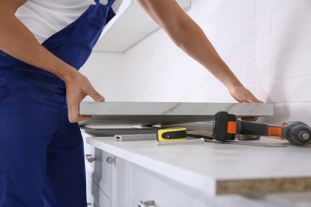 a man is installing a counter top in a kitchen .