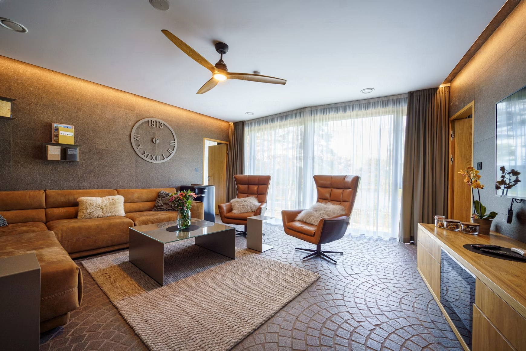 a living room with a couch , chairs , coffee table and ceiling fan .