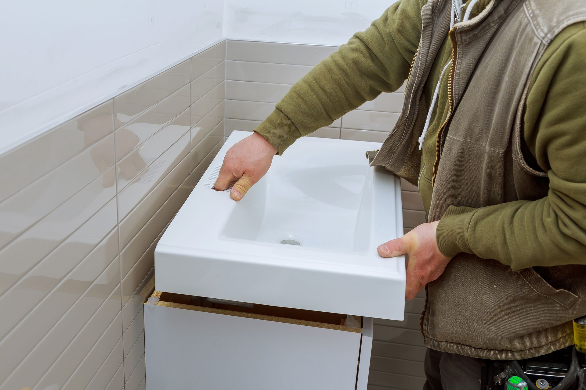 a man is installing a sink in a bathroom .