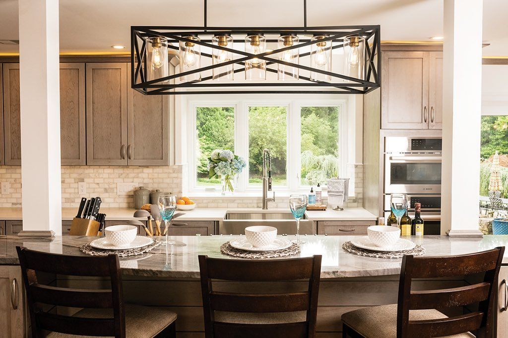 Kitchen with granite countertop island and three stools; window with outdoor view, pendant light.