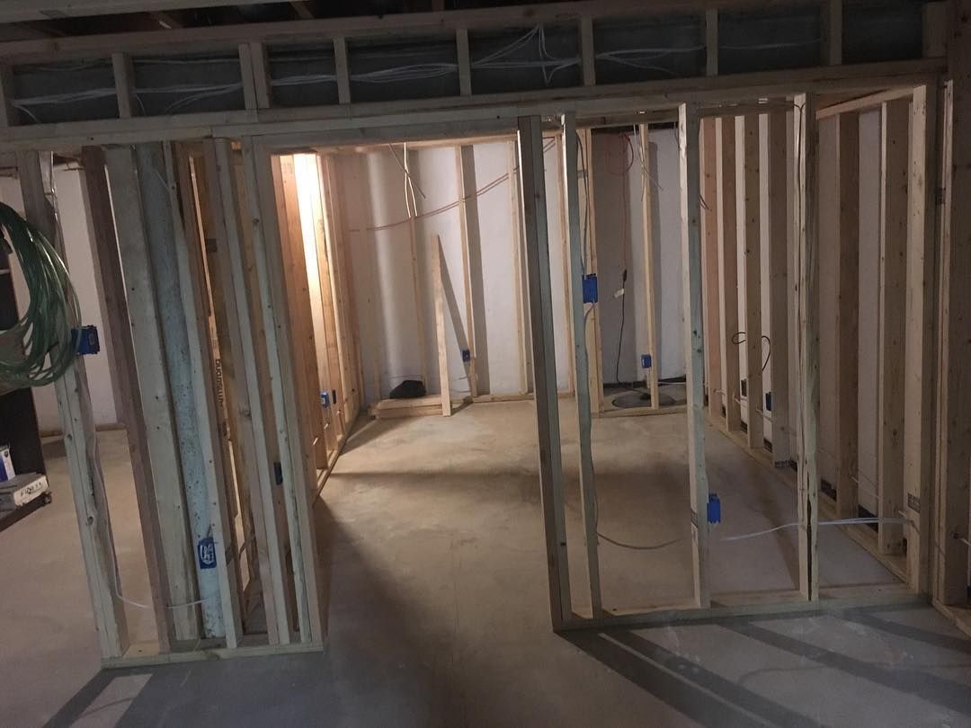 Wooden framing of interior walls in a basement. Electrical boxes are visible, framing a doorway.