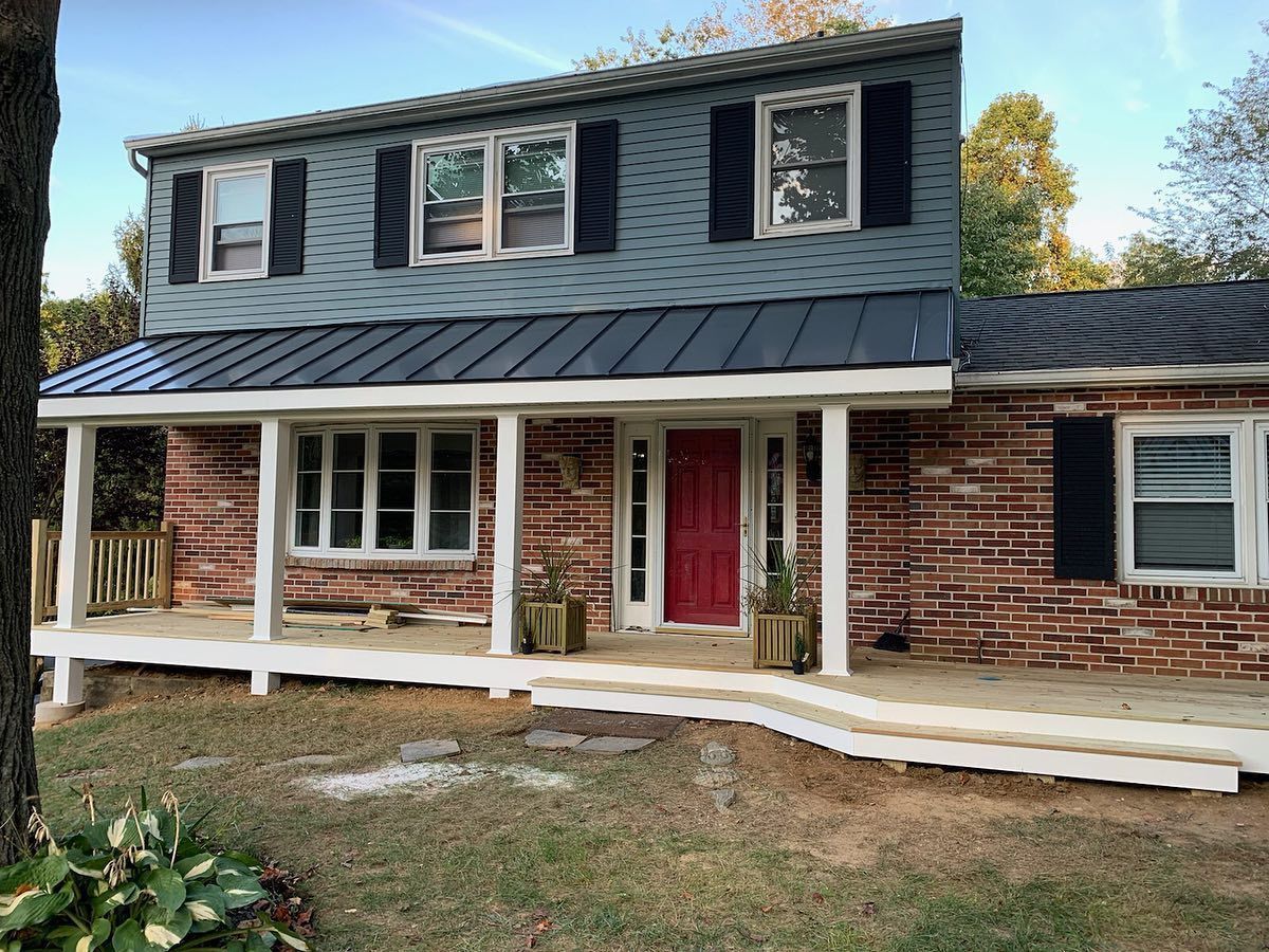 Brick house with a red door, black shutters, and a covered porch with a wheelchair ramp.