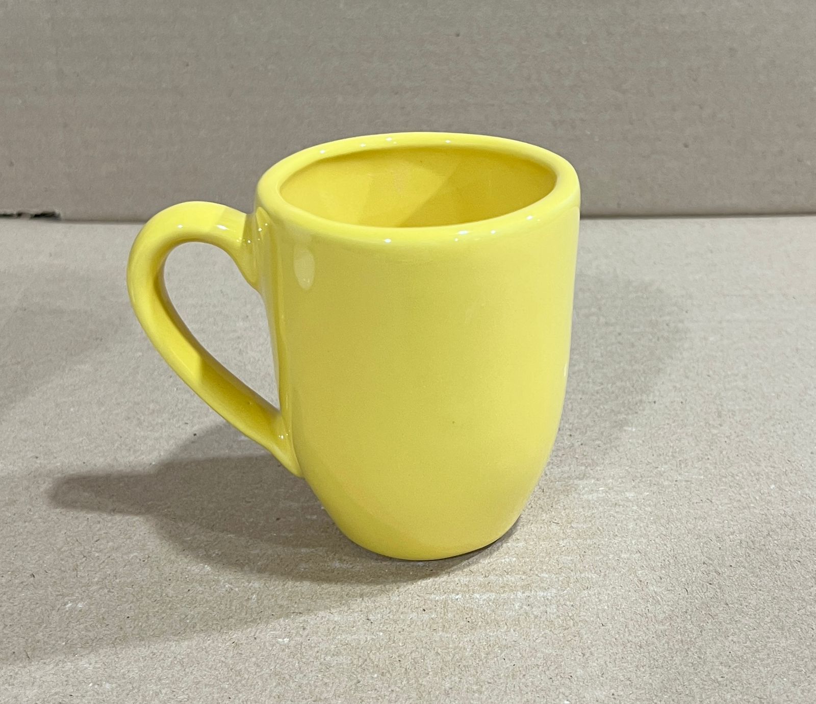 Taza de cerámica amarilla sobre superficie neutra.