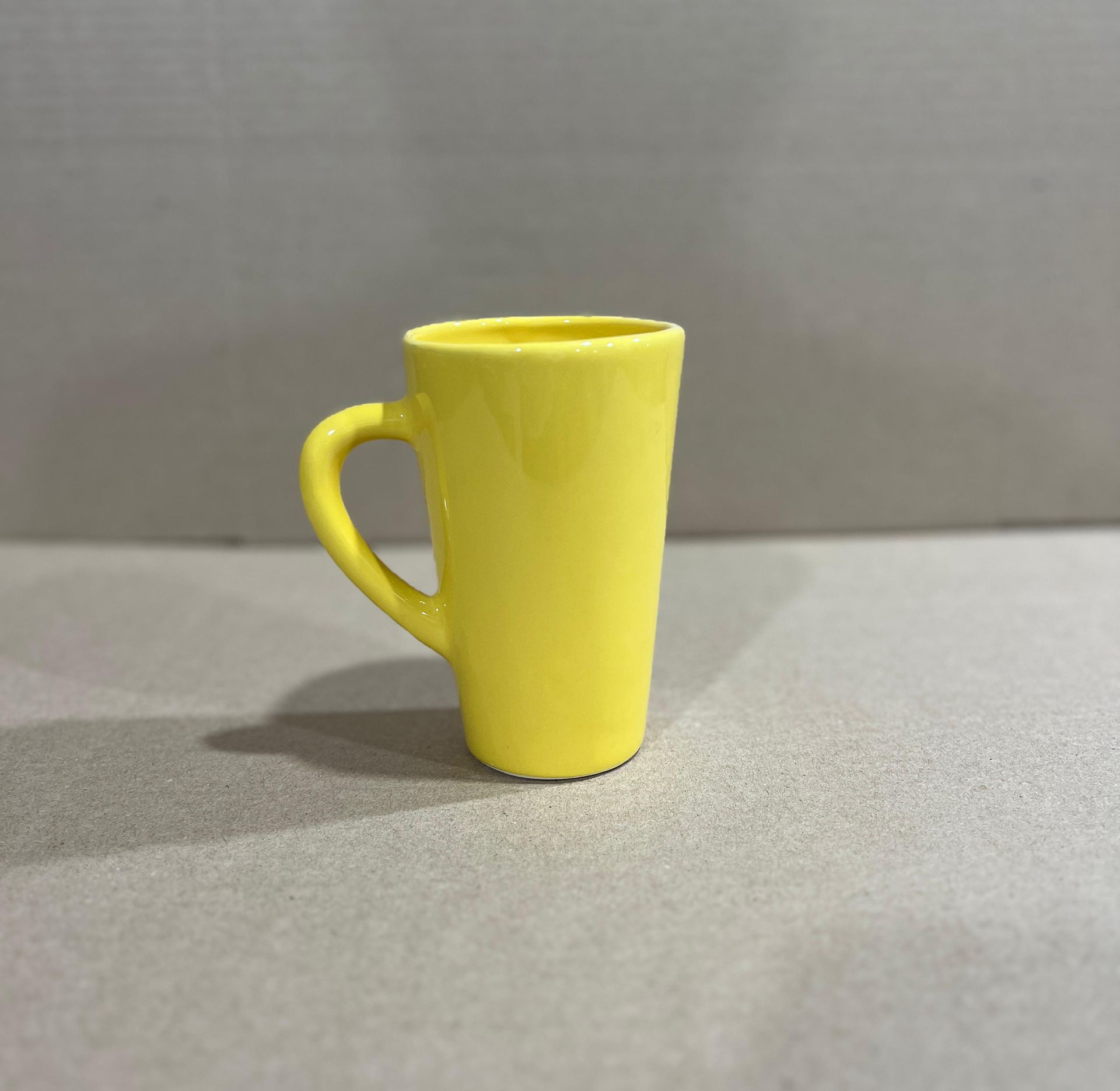 Taza amarilla sobre una superficie gris.