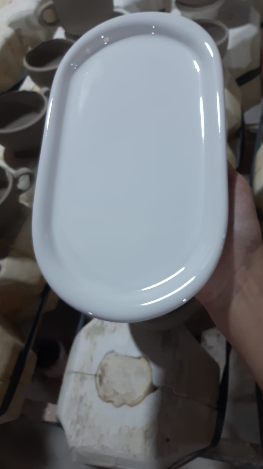 Bandeja de cerámica blanca, ovalada, sostenida en la mano, posiblemente para servir.
