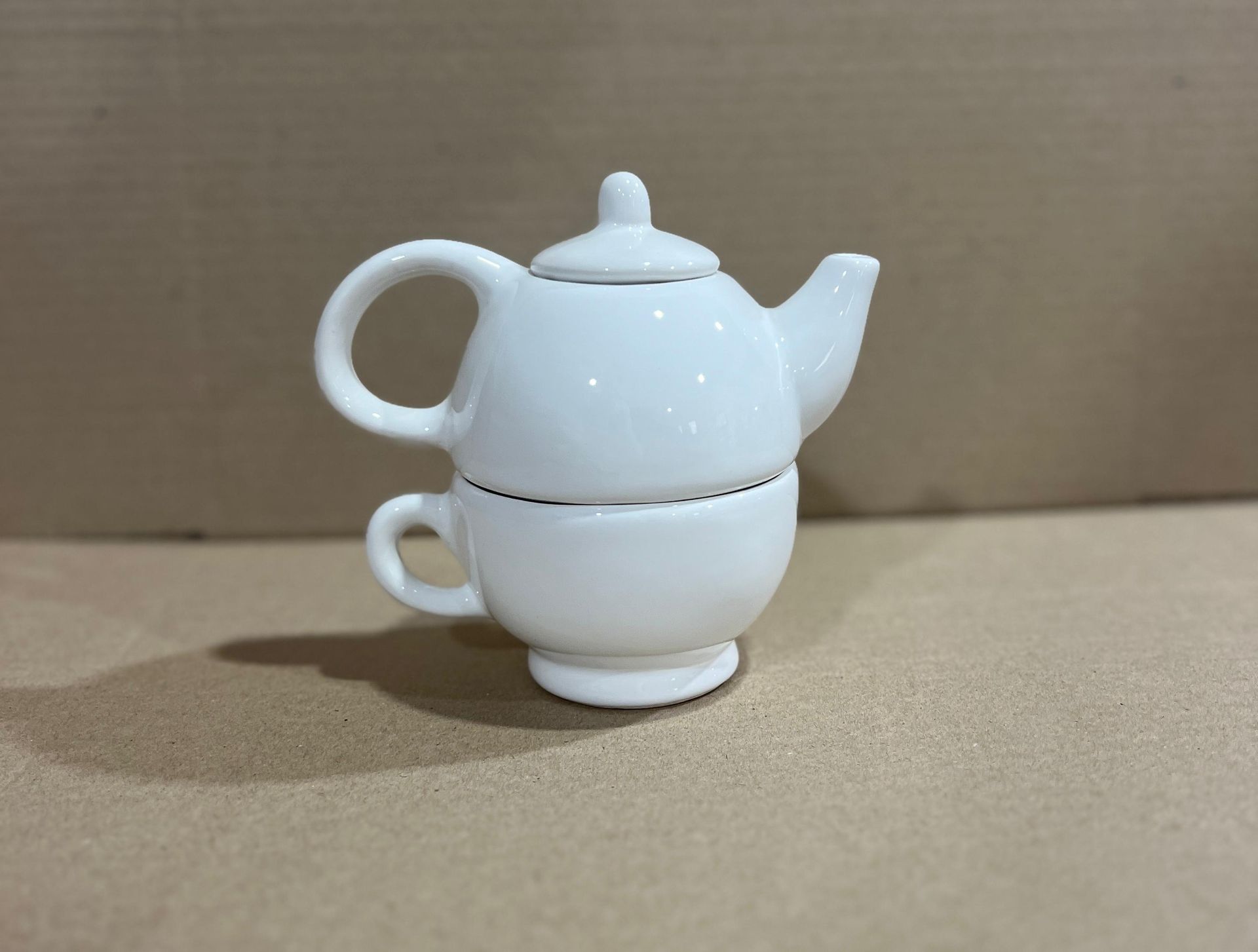 Tetera de cerámica blanca apilada sobre una taza de té.