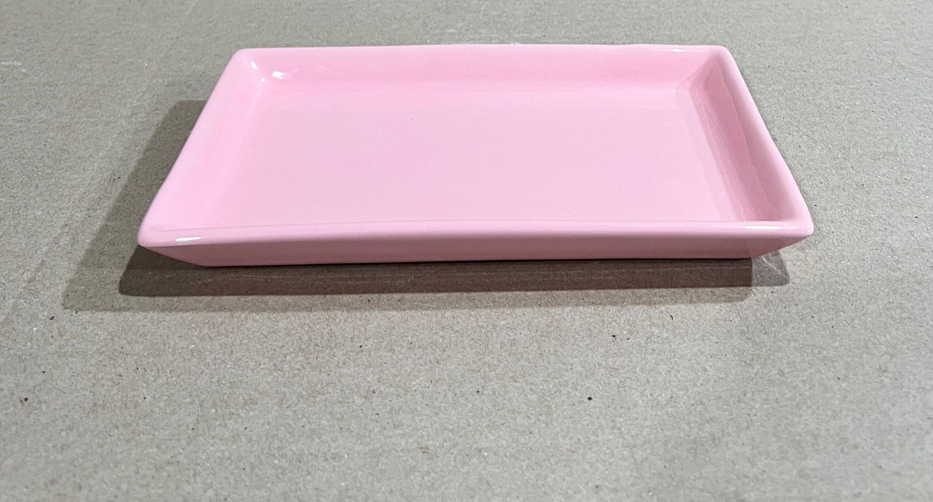 Bandeja rectangular de cerámica de color rosa sobre superficie gris.